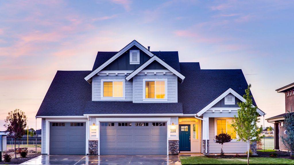 Exterior view of a well-maintained suburban home with a driveway, front lawn, and attached garage at sunset.