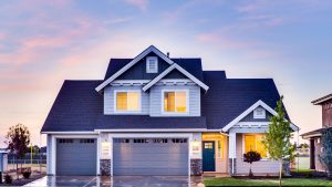 Exterior view of a well-maintained suburban home with a driveway, front lawn, and attached garage at sunset.