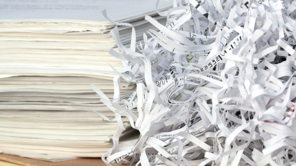 Shredded paper beside stacks of stored documents, representing the transition from records storage to secure document destruction.