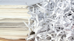 Shredded paper beside stacks of stored documents, representing the transition from records storage to secure document destruction.